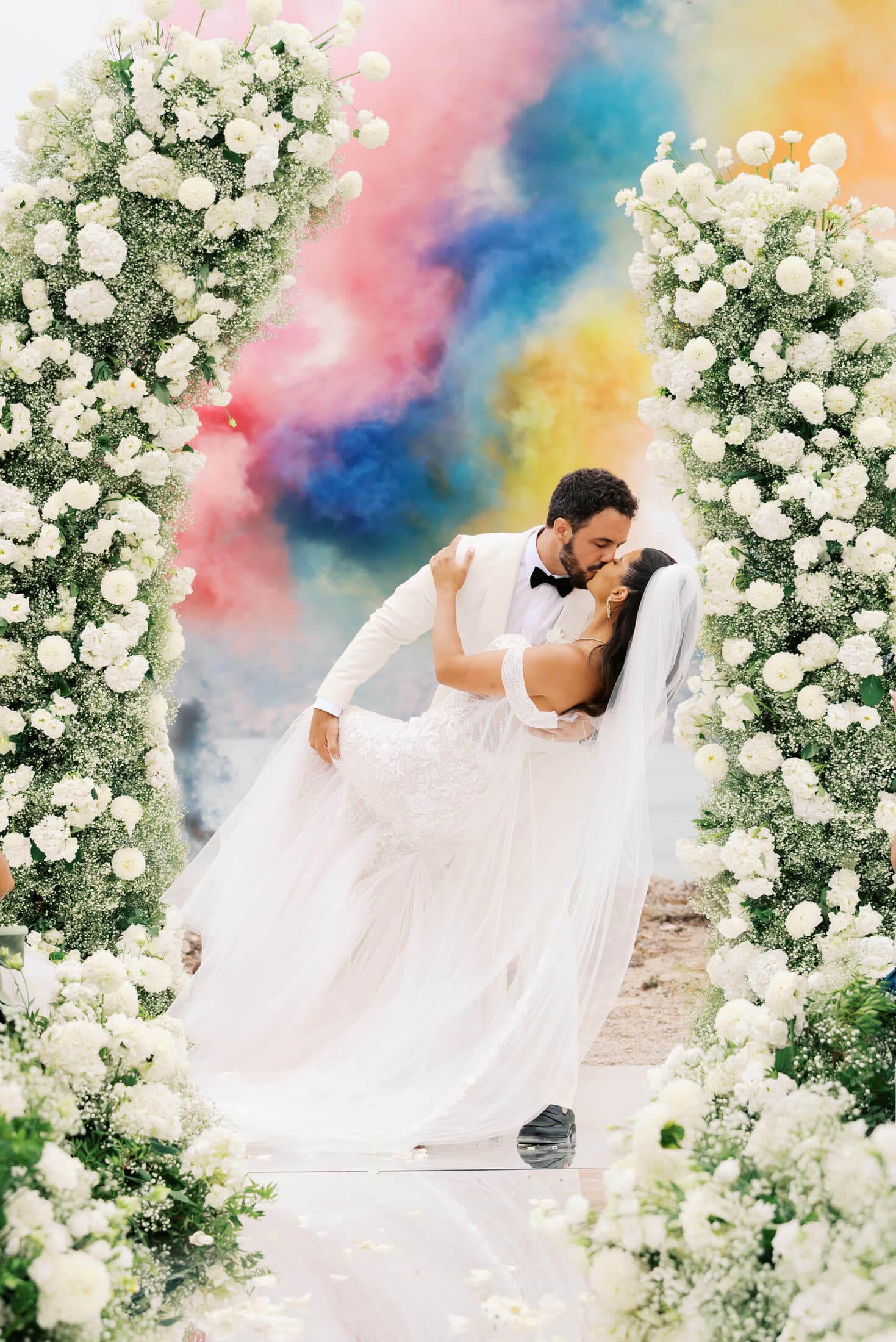 Noivos a dançar sob um arco floral com fumo colorido num casamento em Portugal