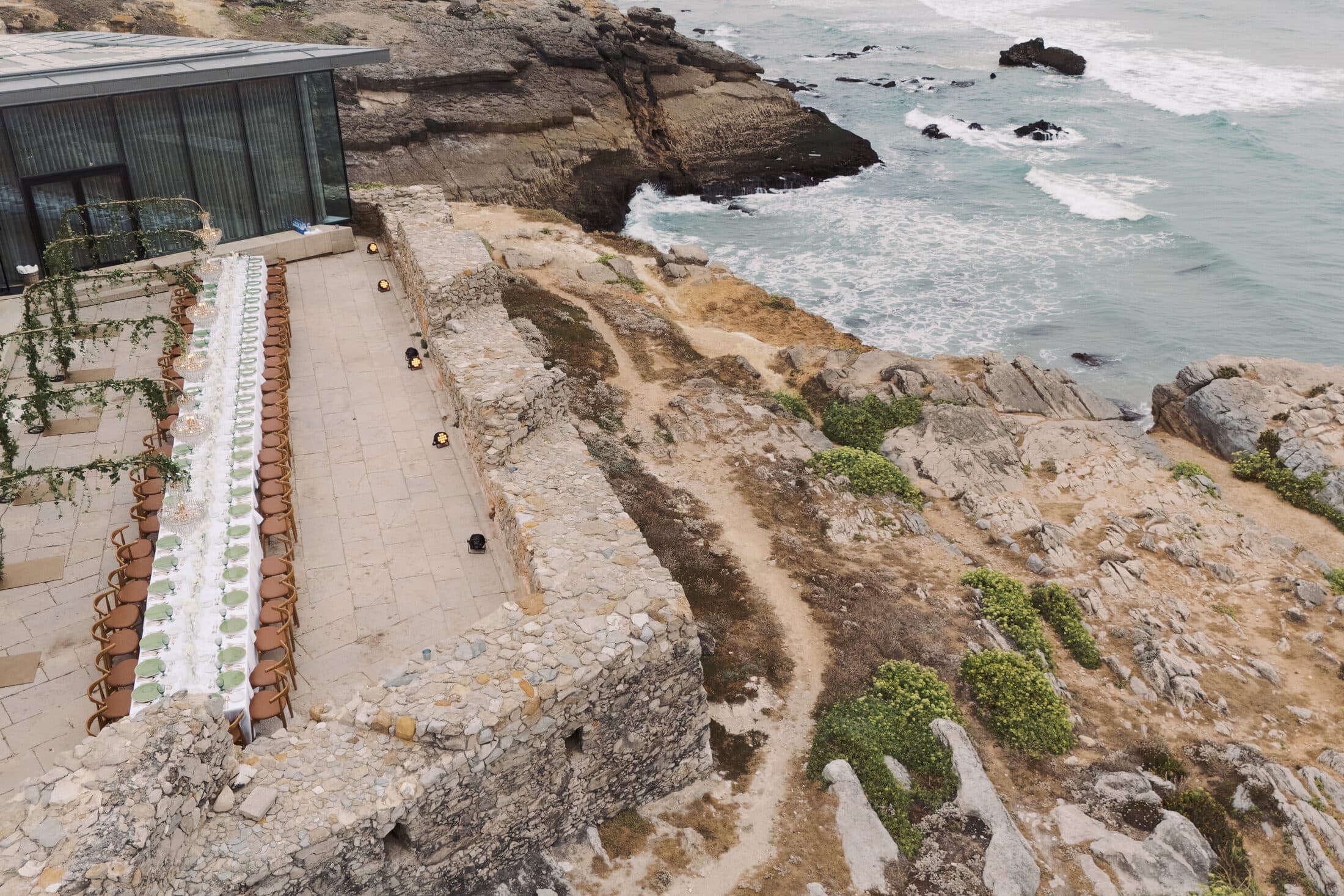 Vista aérea de um espaço de eventos na costa portuguesa com mesa imperial montada